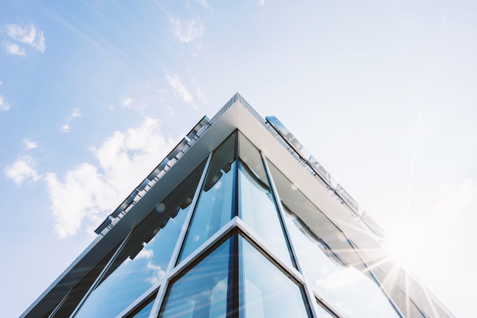Low angle shot of a modern glass building with sun glare reflecting on its surface