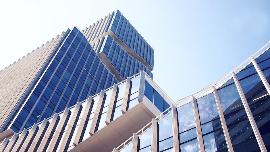 Low-angle shot of a modern skyscraper with reflective glass design under a clear blue sky