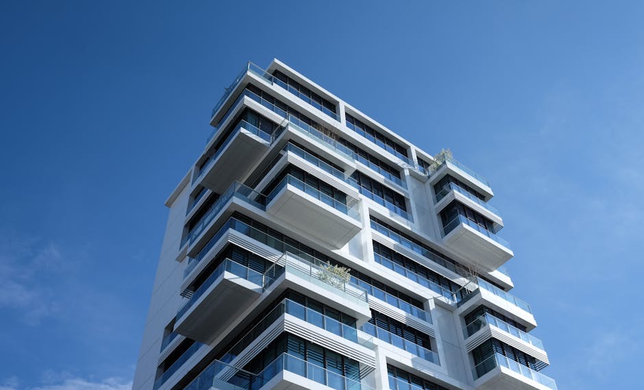 Striking low-angle shot of a modern condominium with unique balcony design and clear blue sky