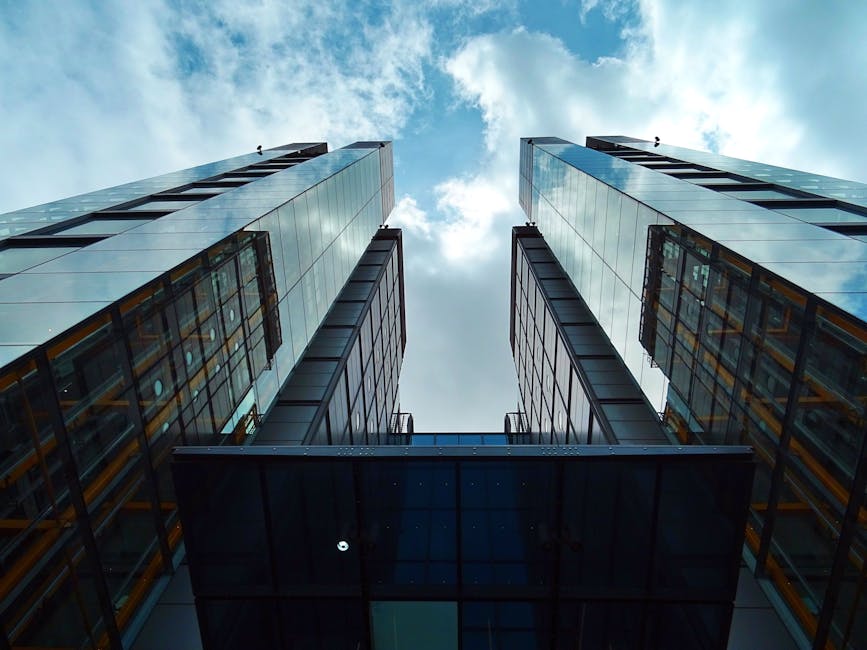 Low-angle view of sleek, modern skyscrapers with glass facades under a blue sky